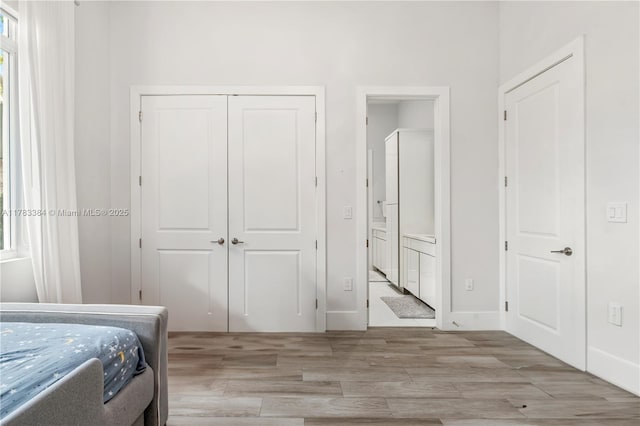 bedroom with a closet, wood finished floors, and ensuite bathroom