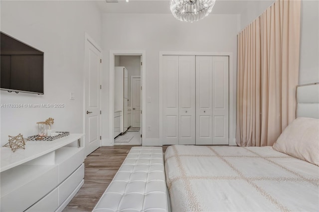bedroom with a closet, a chandelier, and wood finished floors