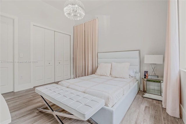 bedroom featuring a closet, light wood finished floors, and a chandelier