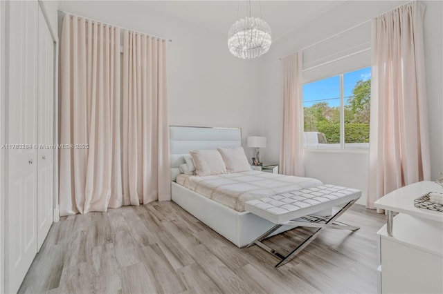 bedroom with light wood-style floors and an inviting chandelier