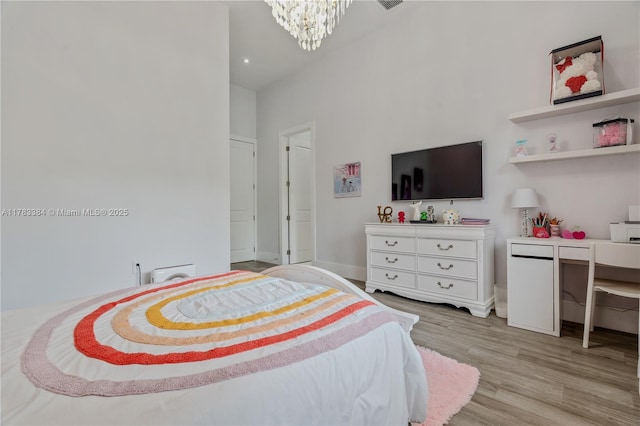 bedroom featuring a chandelier, light wood finished floors, and baseboards