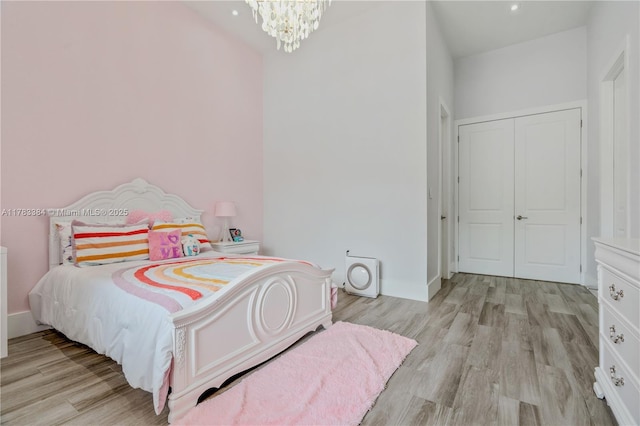 bedroom featuring baseboards, light wood-type flooring, and a notable chandelier