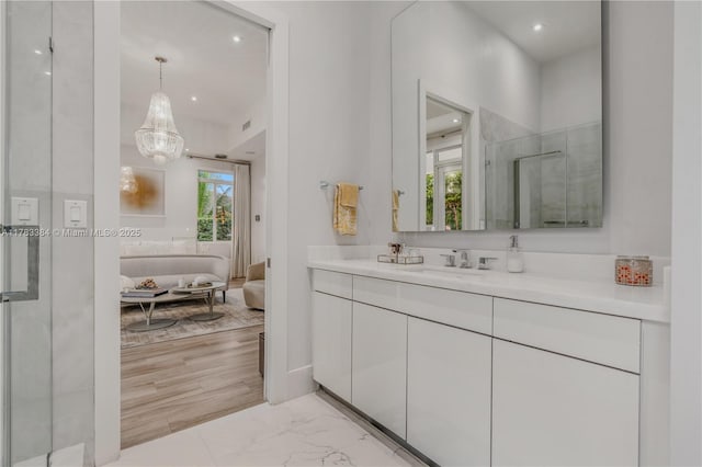 bathroom with marble finish floor, a notable chandelier, vanity, and recessed lighting