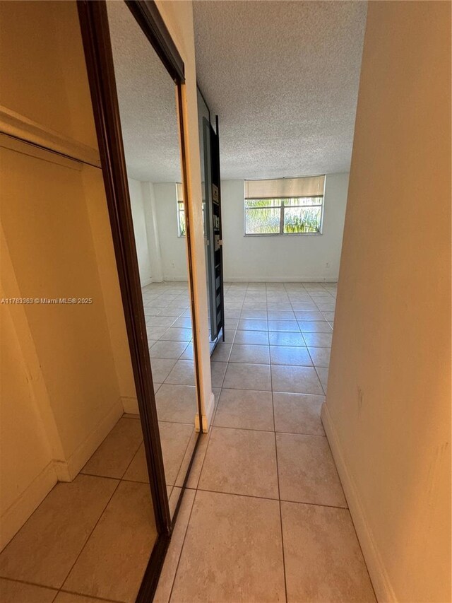 16465 NE 22nd Ave Unit 205, North Miami Beach, FL 33160 - hall with light tile patterned floors, baseboards, and a textured ceiling
