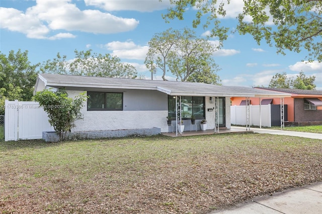 ranch-style house with an attached carport, driveway, fence, and a front lawn