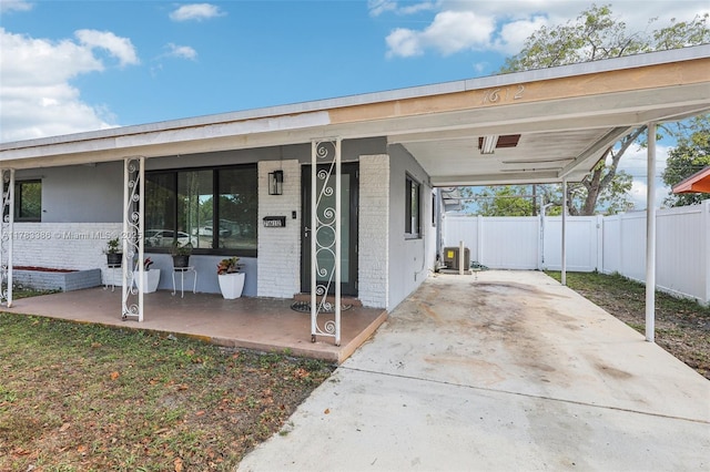 view of front of home with a carport, brick siding, and fence