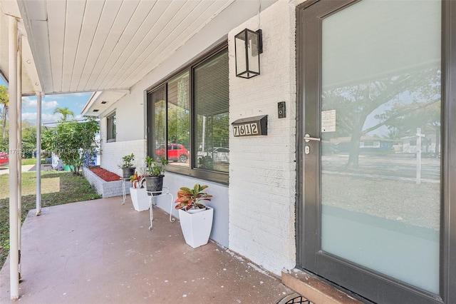 doorway to property with covered porch and brick siding