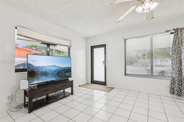 living room with a textured ceiling, ceiling fan, and baseboards