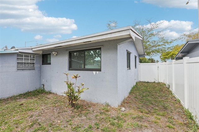 view of property exterior featuring stucco siding and fence