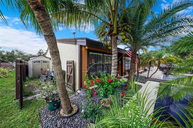 exterior space with a shed, stucco siding, an outdoor structure, and fence