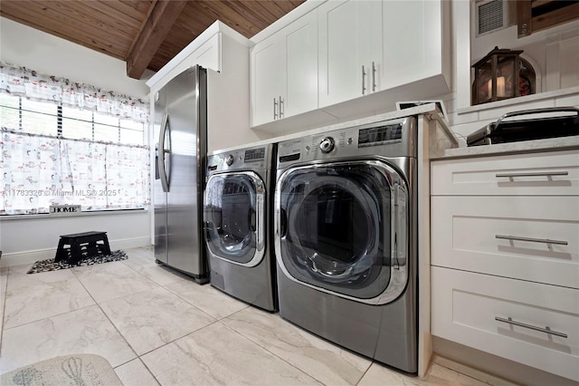 laundry area featuring wood ceiling, baseboards, cabinet space, and washing machine and dryer