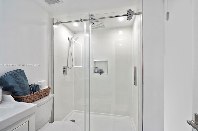 bathroom featuring a shower stall, vanity, visible vents, and toilet