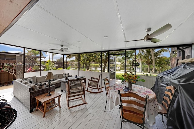 sunroom featuring ceiling fan, outdoor dining area, a water view, and an outdoor hangout area