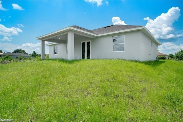 3308 SW 17th St, Lehigh Acres, FL 33971 - back of property with french doors, a shingled roof, stucco siding, and a yard
