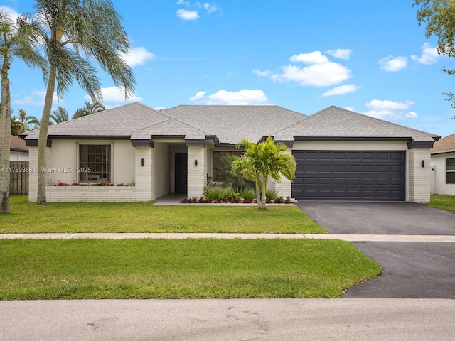 ranch-style house featuring roof with shingles, a front yard, brick siding, a garage, and driveway