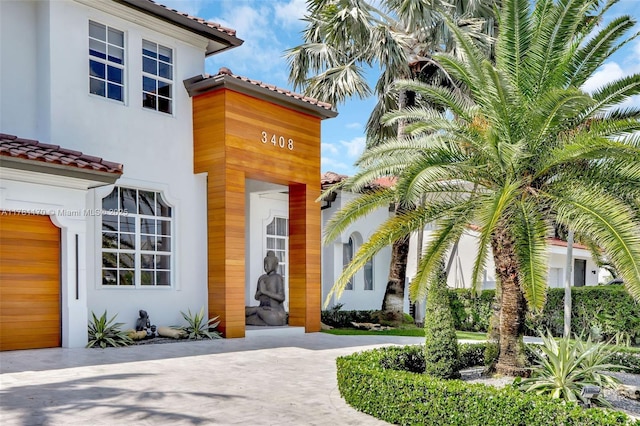 3408 NE 169th St, North Miami Beach, FL 33160 - doorway to property featuring a tiled roof, curved driveway, and stucco siding
