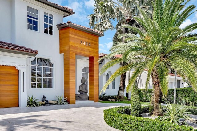 3408 NE 169th St, North Miami Beach, FL 33160 - doorway to property featuring a tiled roof, curved driveway, and stucco siding