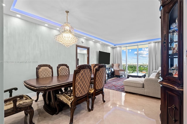 dining space with marble finish floor, a notable chandelier, and a tray ceiling