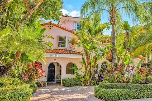 mediterranean / spanish house with a tiled roof and stucco siding