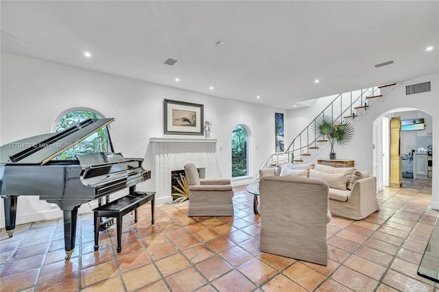 living area with stairway, arched walkways, a healthy amount of sunlight, and visible vents