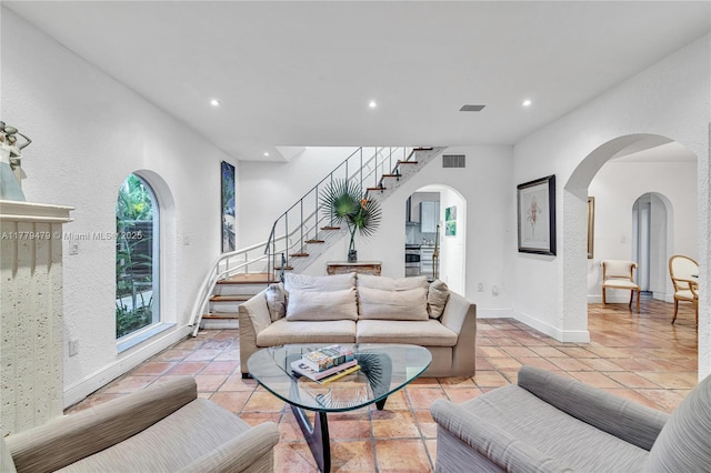 living area with stairway, arched walkways, visible vents, and recessed lighting