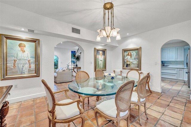 dining room featuring arched walkways, a chandelier, and visible vents