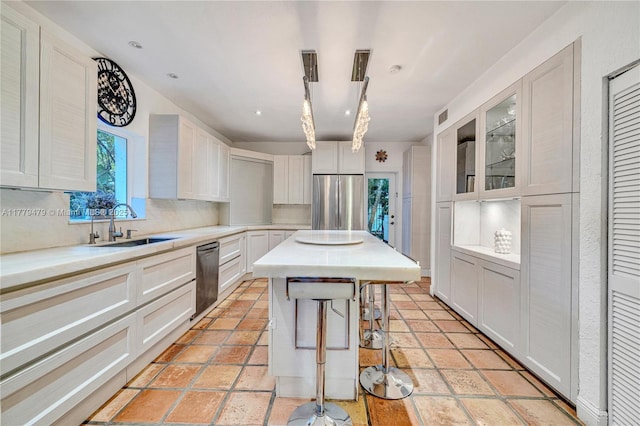 kitchen with a center island, light countertops, decorative backsplash, stainless steel appliances, and a sink