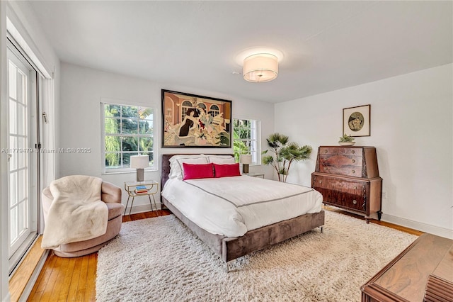 bedroom with baseboards, multiple windows, and wood finished floors