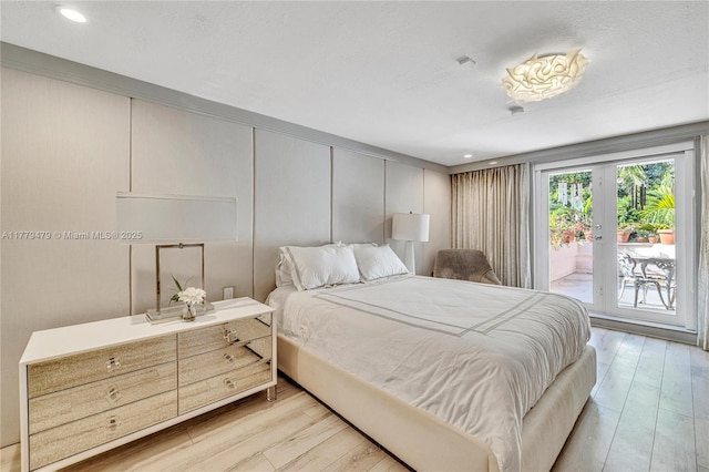 bedroom with light wood finished floors, french doors, a decorative wall, and access to exterior