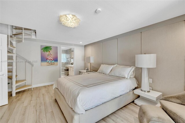 bedroom with light wood finished floors, ensuite bathroom, and baseboards