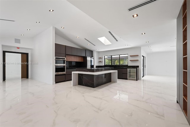 kitchen featuring a center island, beverage cooler, modern cabinets, visible vents, and vaulted ceiling with skylight