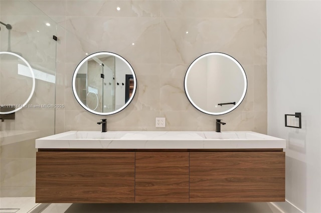 bathroom featuring tile walls, walk in shower, double vanity, and a sink