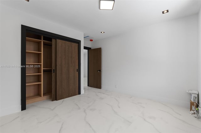 unfurnished bedroom with a closet and marble finish floor