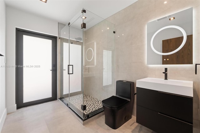 full bathroom featuring a stall shower, tile walls, vanity, and toilet
