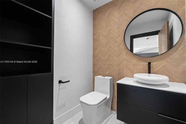 bathroom with wallpapered walls, toilet, and vanity