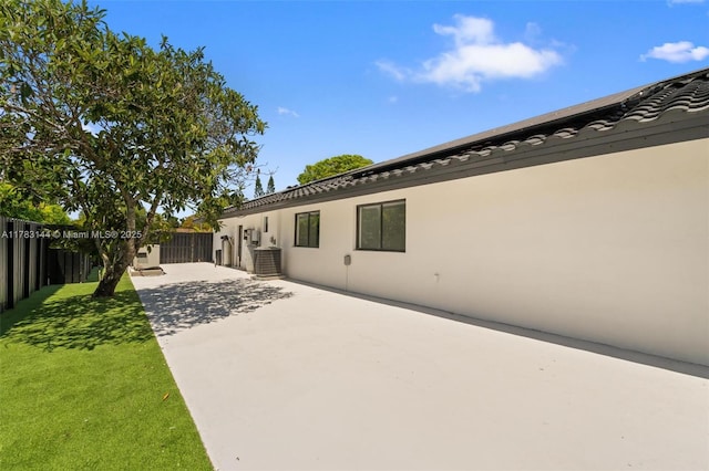 back of house with stucco siding, a tiled roof, fence, and a patio