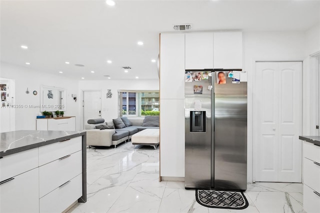 5117 Washington St, Hollywood, FL 33021 - kitchen with stainless steel fridge with ice dispenser, white cabinets, visible vents, marble finish floor, and dark countertops