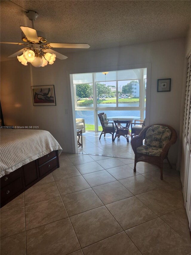 2114 E Cambridge E Unit 2114, Deerfield Beach, FL 33442 - bedroom with a water view, a ceiling fan, a textured ceiling, access to exterior, and tile patterned flooring