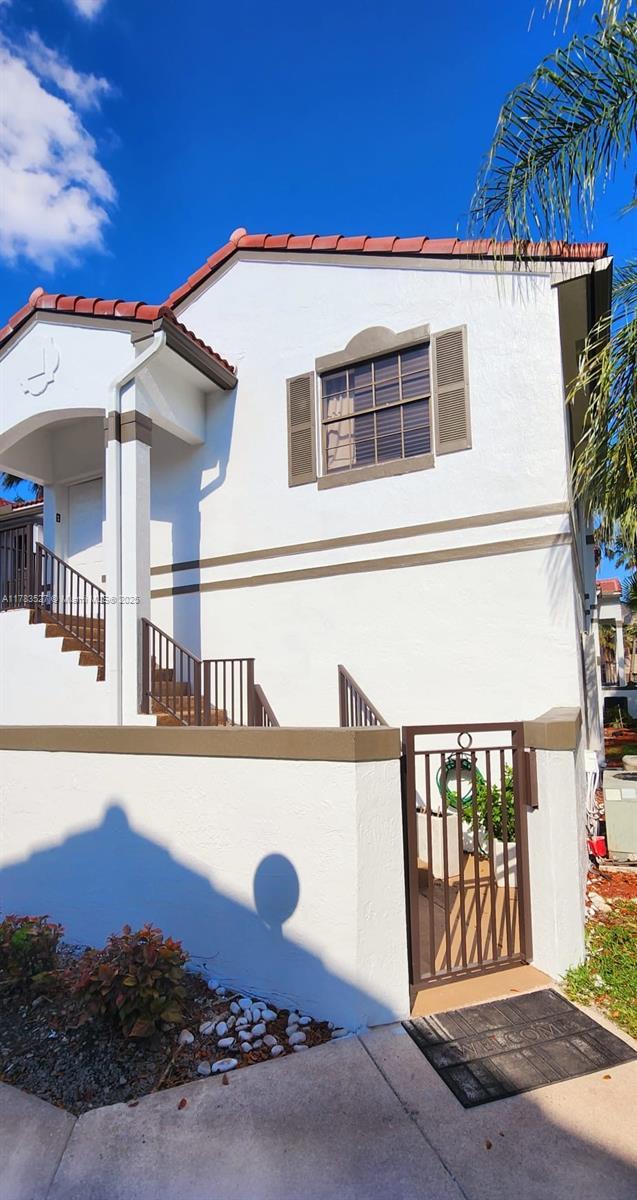 mediterranean / spanish house with a fenced front yard, a tiled roof, a gate, and stucco siding