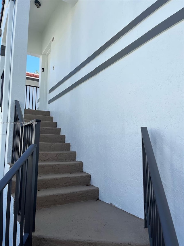 staircase featuring a textured wall and concrete flooring