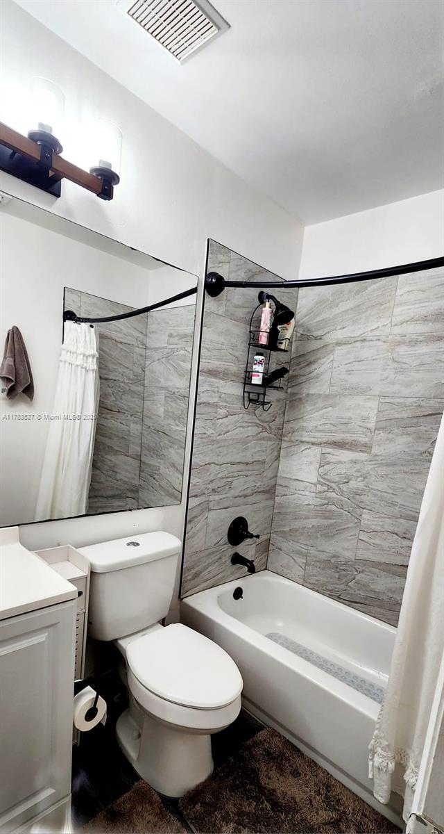 full bath featuring vanity, visible vents, shower / bathtub combination with curtain, and toilet