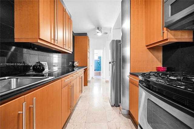 kitchen featuring brown cabinetry, dark countertops, backsplash, and appliances with stainless steel finishes