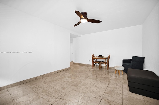 living area with baseboards, a ceiling fan, and marble finish floor