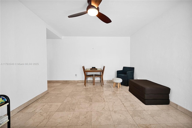 living area with marble finish floor, baseboards, and a ceiling fan