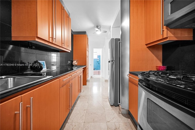 kitchen with stainless steel appliances, baseboards, backsplash, and dark countertops