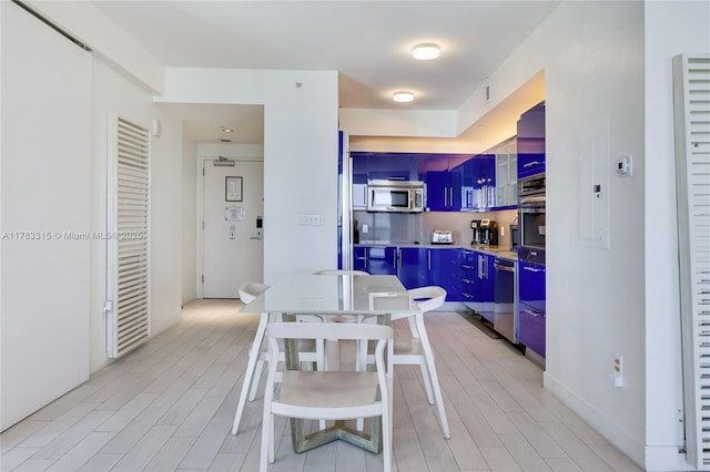 kitchen featuring light countertops, light wood-style floors, stainless steel microwave, and blue cabinetry