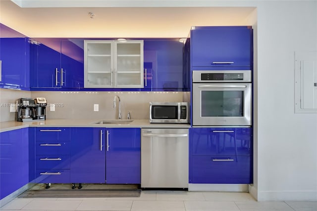 kitchen with glass insert cabinets, electric panel, appliances with stainless steel finishes, light countertops, and a sink
