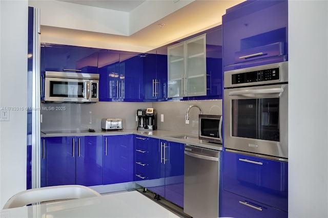 kitchen featuring appliances with stainless steel finishes, a sink, modern cabinets, and glass insert cabinets