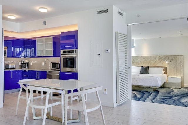 kitchen with glass insert cabinets, visible vents, blue cabinetry, and appliances with stainless steel finishes