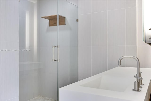 full bath featuring tile walls, a sink, and a stall shower
